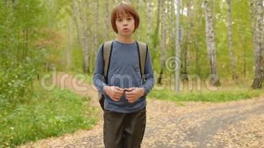 <strong>男</strong>孩少年背着背包走在秋天公园的绿树背景上。 <strong>帅气</strong>的少年<strong>男</strong>孩在路上